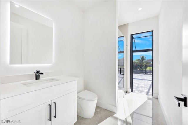 bathroom with baseboards, vanity, and toilet