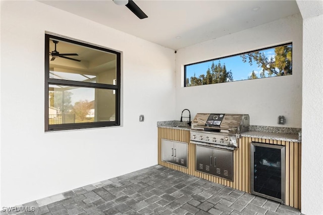 view of patio / terrace featuring an outdoor kitchen, ceiling fan, wine cooler, grilling area, and a sink