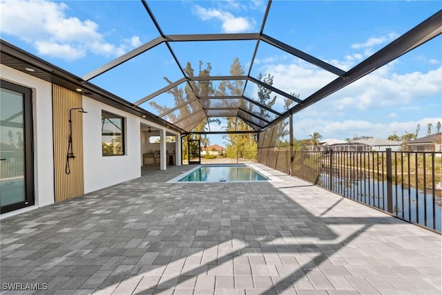 view of swimming pool with a lanai, a water view, a patio area, and a fenced in pool