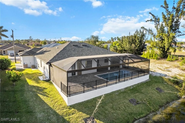 rear view of property featuring a shingled roof, an outdoor pool, glass enclosure, a yard, and a patio area