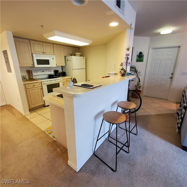 kitchen with white appliances, kitchen peninsula, light brown cabinets, a breakfast bar area, and light colored carpet