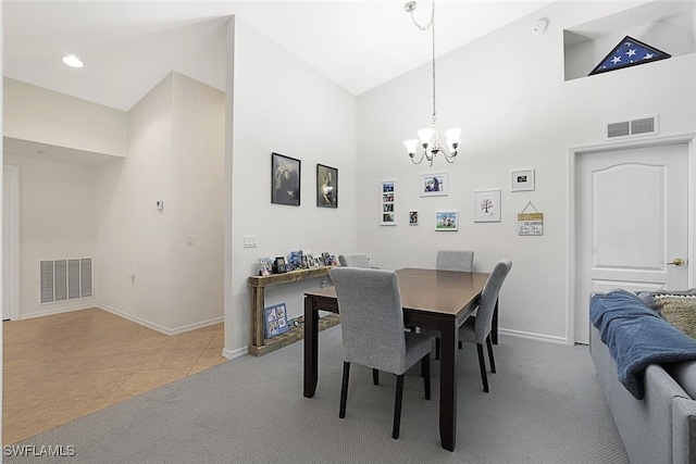 carpeted dining space featuring high vaulted ceiling and an inviting chandelier