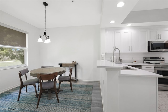 kitchen with pendant lighting, kitchen peninsula, dark hardwood / wood-style floors, white cabinets, and appliances with stainless steel finishes