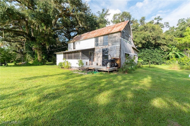 back of property featuring a sunroom and a yard