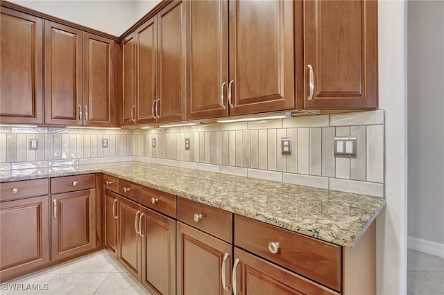 kitchen with light stone countertops, decorative backsplash, and light tile patterned floors