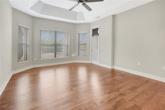 empty room featuring light hardwood / wood-style floors, a raised ceiling, and ceiling fan