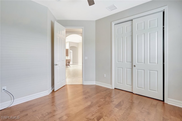 unfurnished bedroom with ceiling fan, a closet, and light wood-type flooring