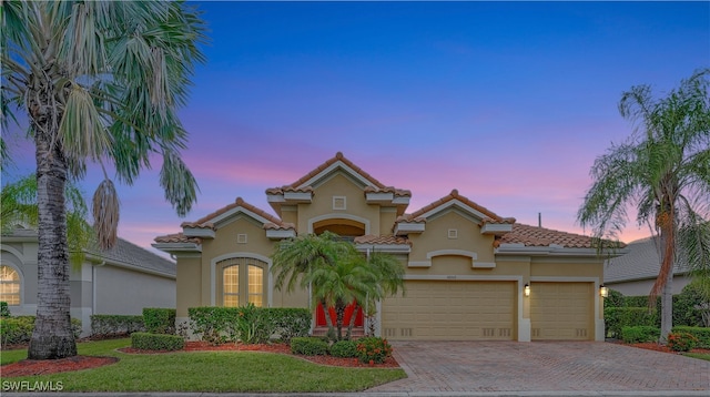 mediterranean / spanish-style home with a lawn and a garage