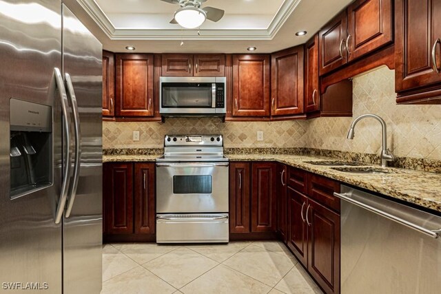 kitchen featuring a raised ceiling, sink, appliances with stainless steel finishes, light tile patterned floors, and light stone counters