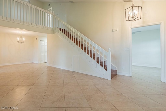 staircase featuring a chandelier, tile patterned floors, and a high ceiling