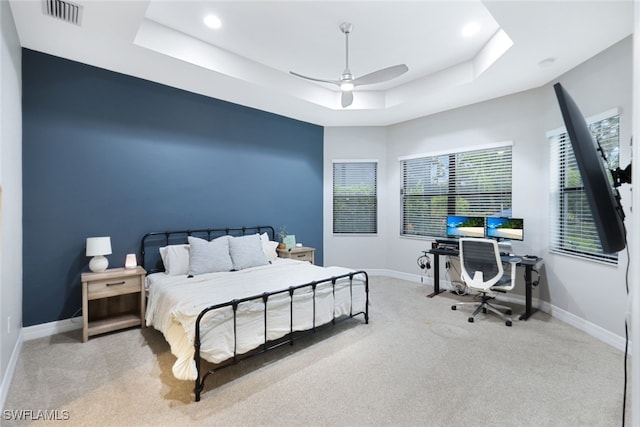 bedroom featuring light carpet, a raised ceiling, and ceiling fan