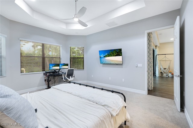 carpeted bedroom featuring a raised ceiling and ceiling fan