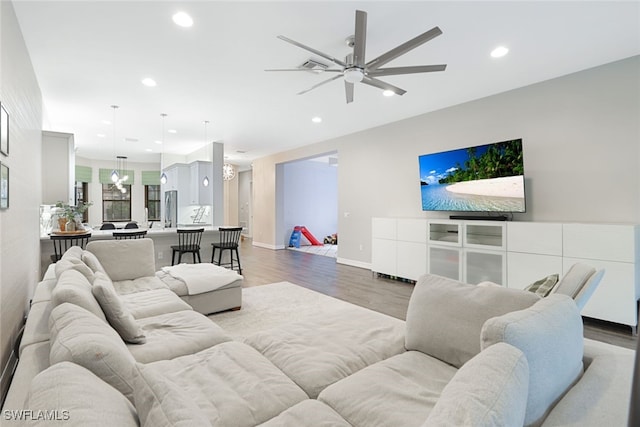 living room with wood-type flooring and ceiling fan with notable chandelier