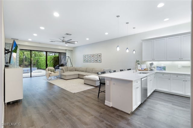 kitchen featuring kitchen peninsula, white cabinets, a breakfast bar area, dishwasher, and decorative light fixtures