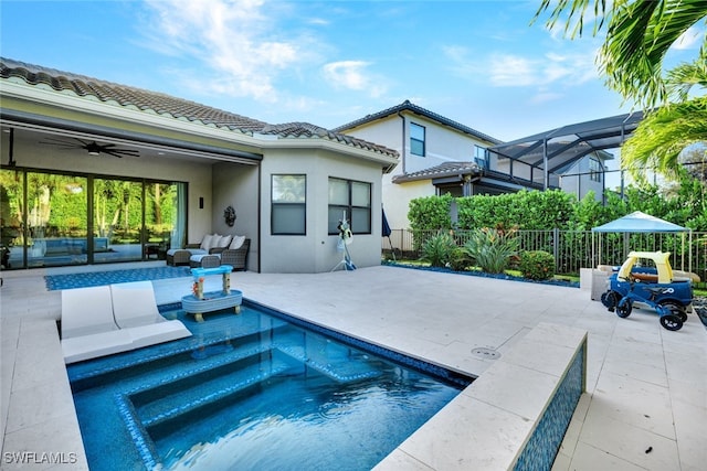 view of swimming pool featuring an outdoor hangout area, a patio area, glass enclosure, and ceiling fan