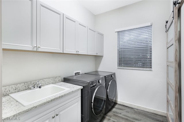 washroom featuring hardwood / wood-style flooring, sink, a barn door, cabinets, and washing machine and dryer