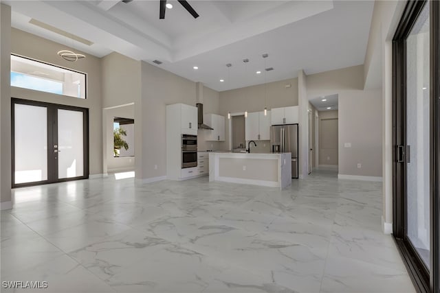 kitchen featuring appliances with stainless steel finishes, hanging light fixtures, white cabinetry, an island with sink, and ceiling fan