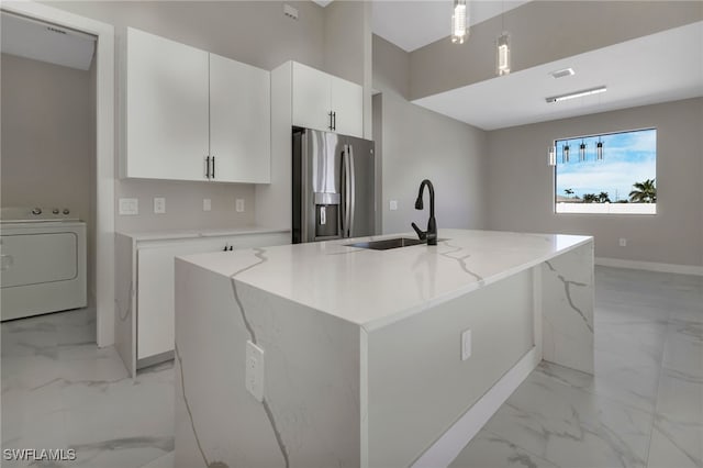 kitchen with stainless steel fridge, sink, a kitchen island with sink, white cabinetry, and washer / clothes dryer