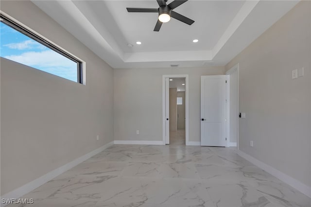 empty room featuring ceiling fan and a tray ceiling