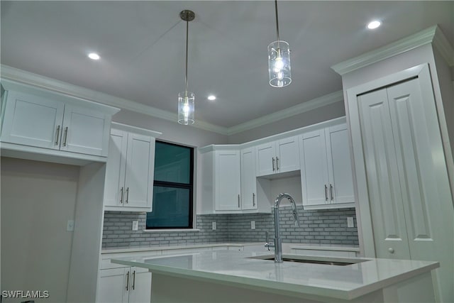 kitchen featuring white cabinets, a center island with sink, hanging light fixtures, and sink