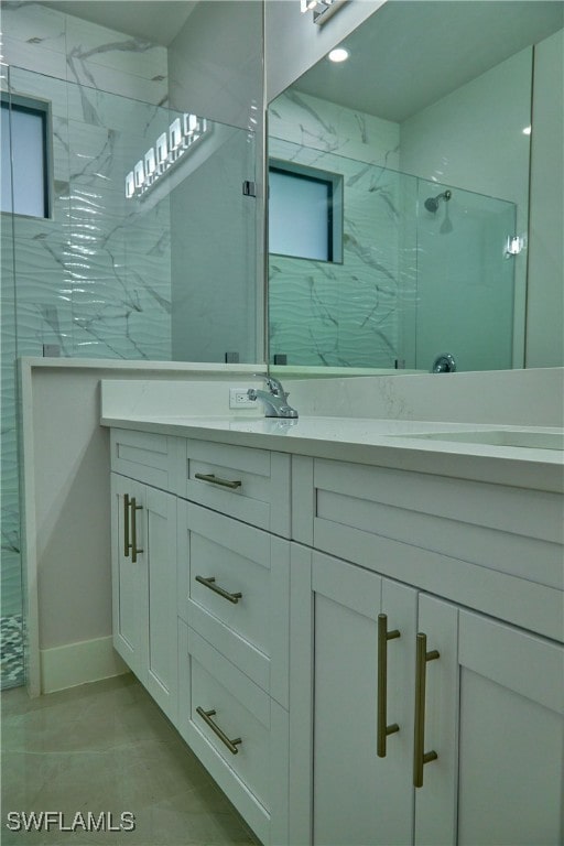 bathroom featuring vanity, a tile shower, and tile patterned floors