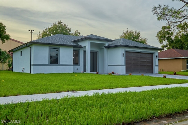 prairie-style home featuring a lawn and a garage