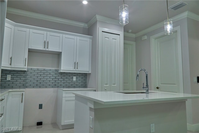 kitchen with an island with sink, white cabinetry, and pendant lighting