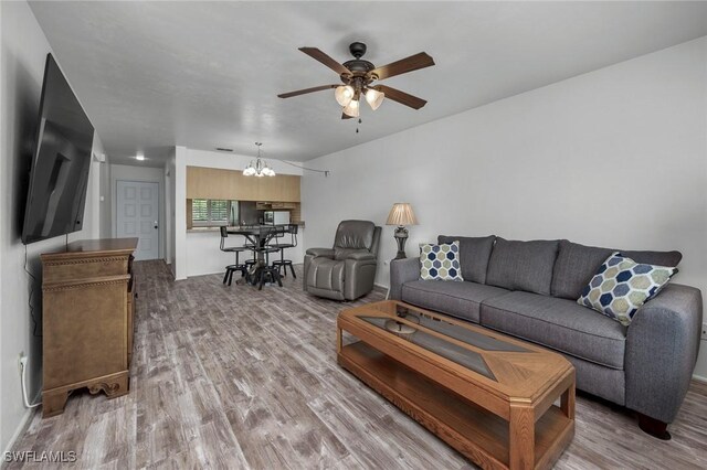 living room with wood-type flooring and ceiling fan with notable chandelier