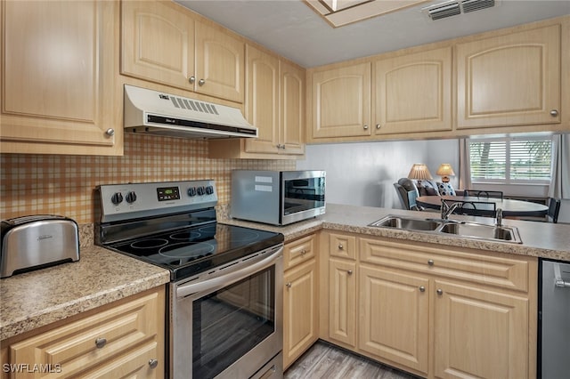 kitchen with stainless steel appliances, light hardwood / wood-style floors, and light brown cabinetry