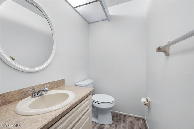 bathroom with wood-type flooring, vanity, and toilet