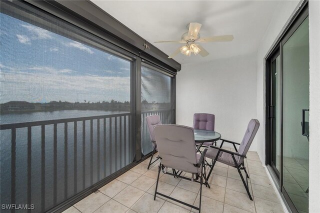 sunroom featuring ceiling fan and a water view