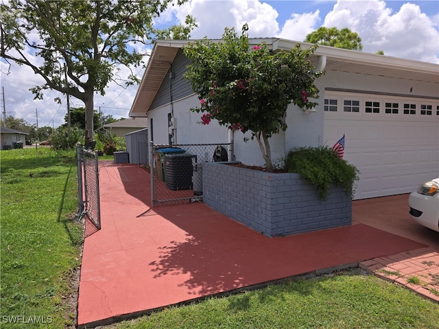 view of side of home with a yard, a garage, and central AC