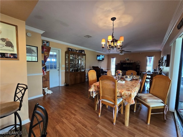 dining area with a healthy amount of sunlight, ceiling fan with notable chandelier, and dark wood-type flooring