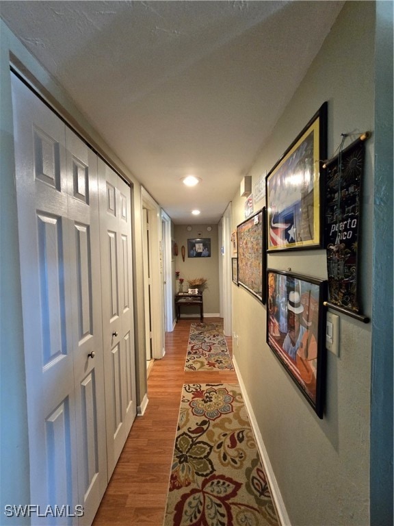 corridor featuring light wood-type flooring and a textured ceiling