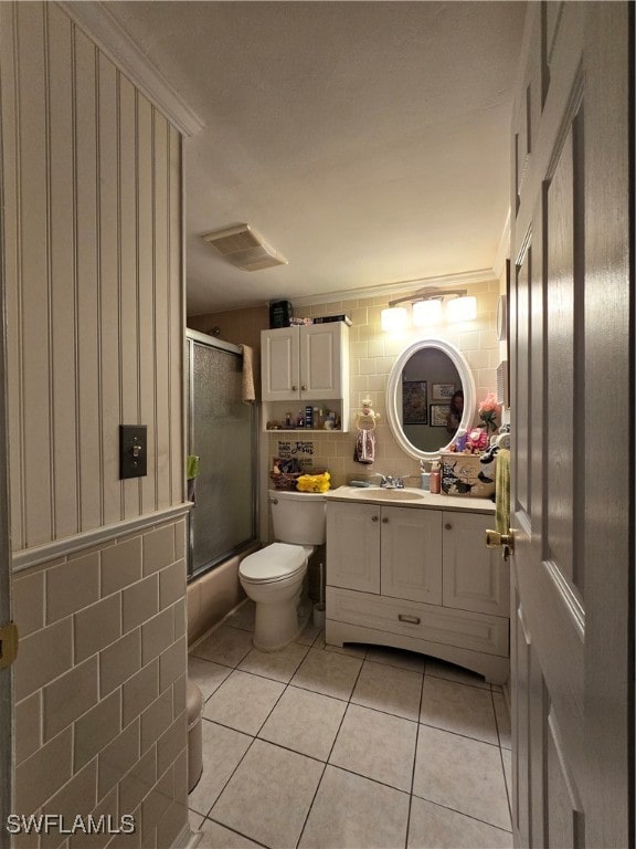 full bathroom featuring tile walls, vanity, shower / bath combination with glass door, toilet, and tile patterned floors