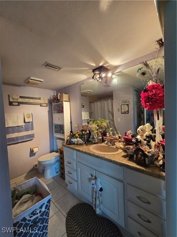 bathroom with a textured ceiling, vanity, toilet, and tile patterned floors