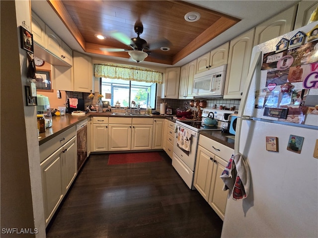 kitchen with white appliances, a raised ceiling, dark wood-type flooring, and sink