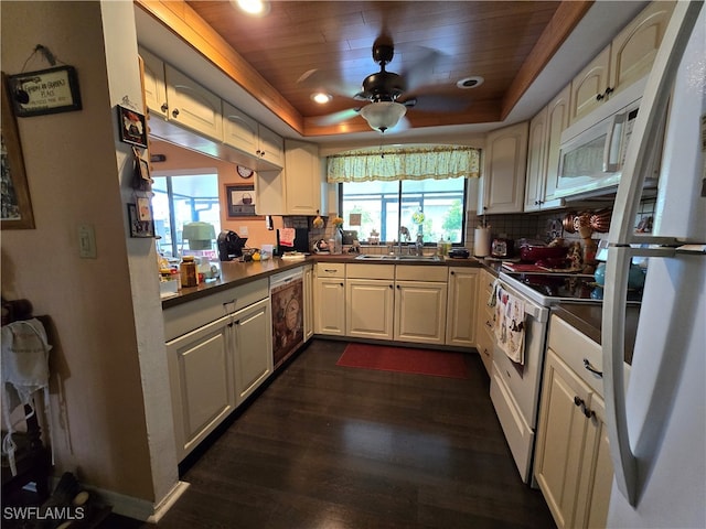 kitchen featuring white appliances, a tray ceiling, ceiling fan, dark hardwood / wood-style floors, and sink