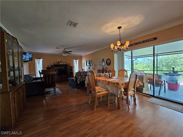 dining area with ceiling fan with notable chandelier, a fireplace, ornamental molding, and dark hardwood / wood-style floors