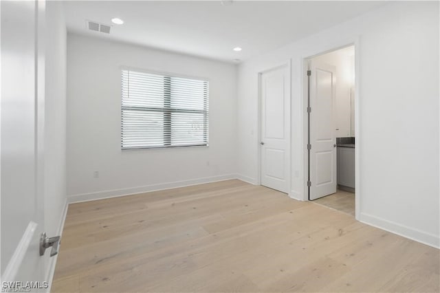 unfurnished bedroom with light wood-type flooring and connected bathroom