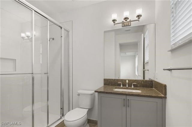 bathroom with vanity, a shower with door, and toilet