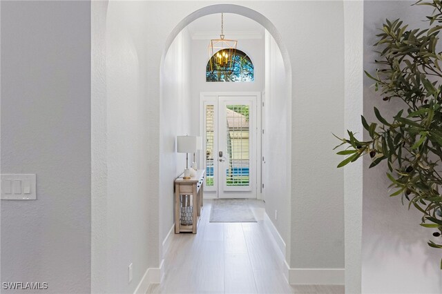 entryway with crown molding, light hardwood / wood-style flooring, and a notable chandelier