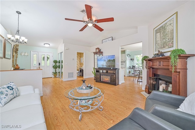 living room with lofted ceiling, hardwood / wood-style floors, and ceiling fan with notable chandelier