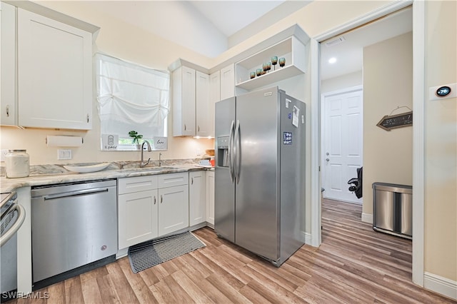 kitchen featuring stainless steel appliances, white cabinetry, and light hardwood / wood-style floors