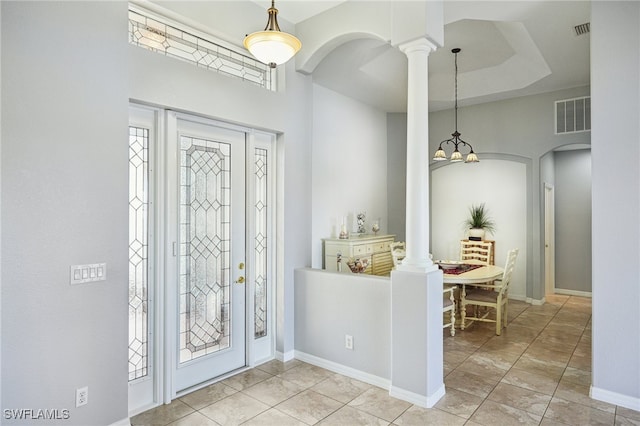 tiled foyer entrance with decorative columns and a tray ceiling