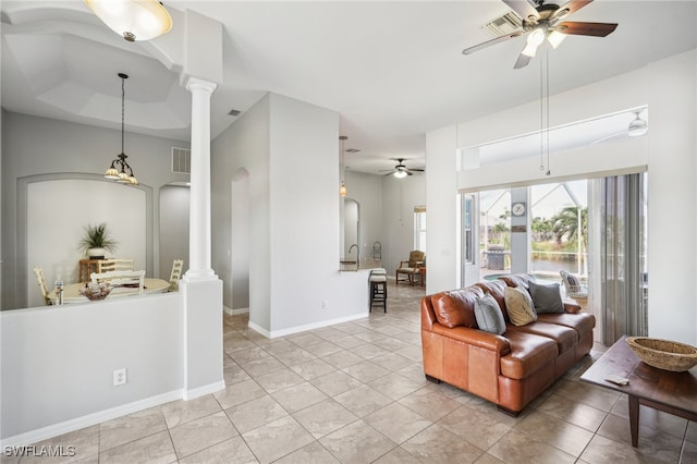 living room with ceiling fan, light tile patterned flooring, ornate columns, and a tray ceiling