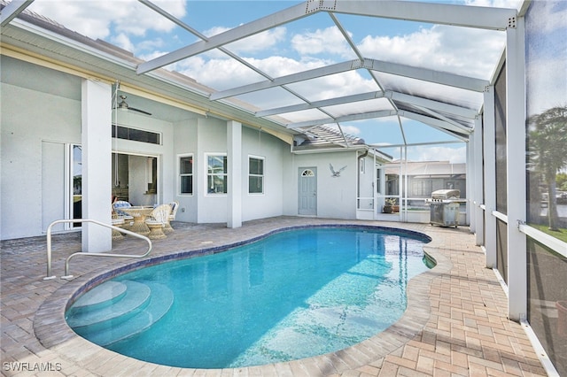 view of swimming pool featuring ceiling fan, area for grilling, a lanai, and a patio