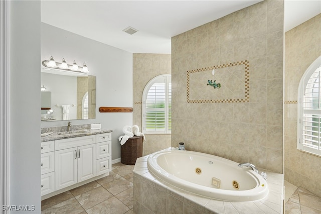 bathroom with tiled bath, tile patterned flooring, and vanity