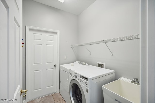 laundry area with independent washer and dryer, light tile patterned floors, and sink