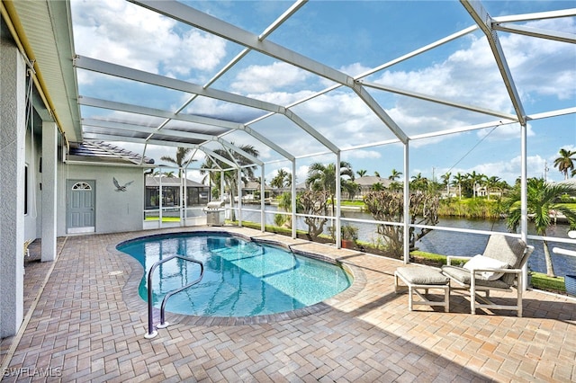 view of swimming pool featuring glass enclosure, a water view, and a patio